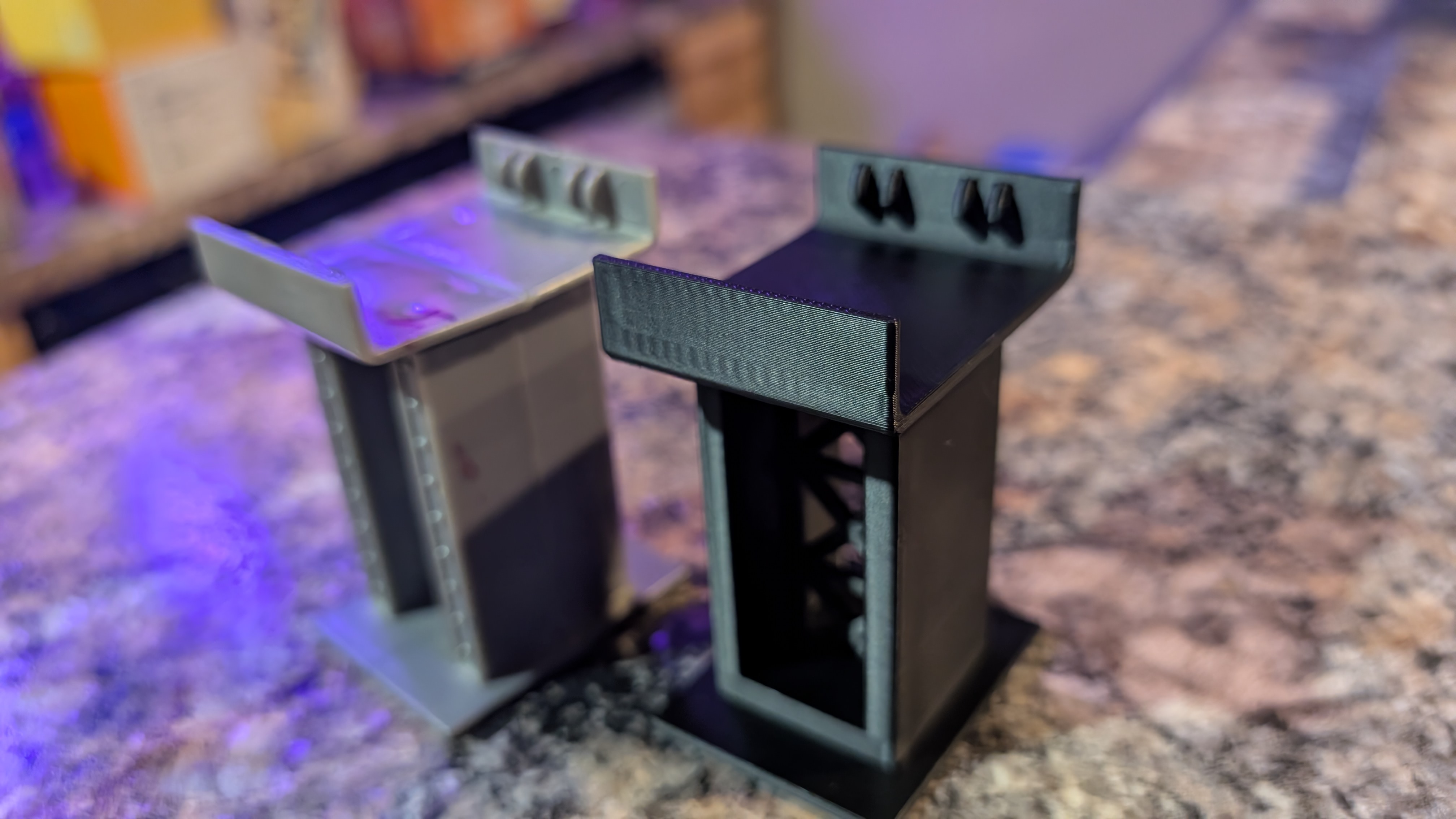 Several black 3D-printed mounting brackets produced during prototype iteration